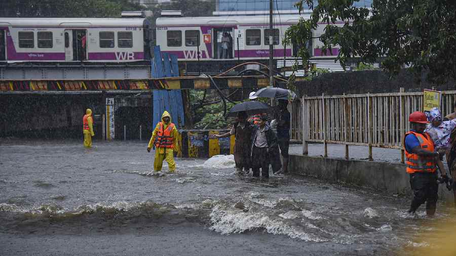 People wade through a waterlogged street amid monsoon rains, near the closed Andheri Subway in Mumbai