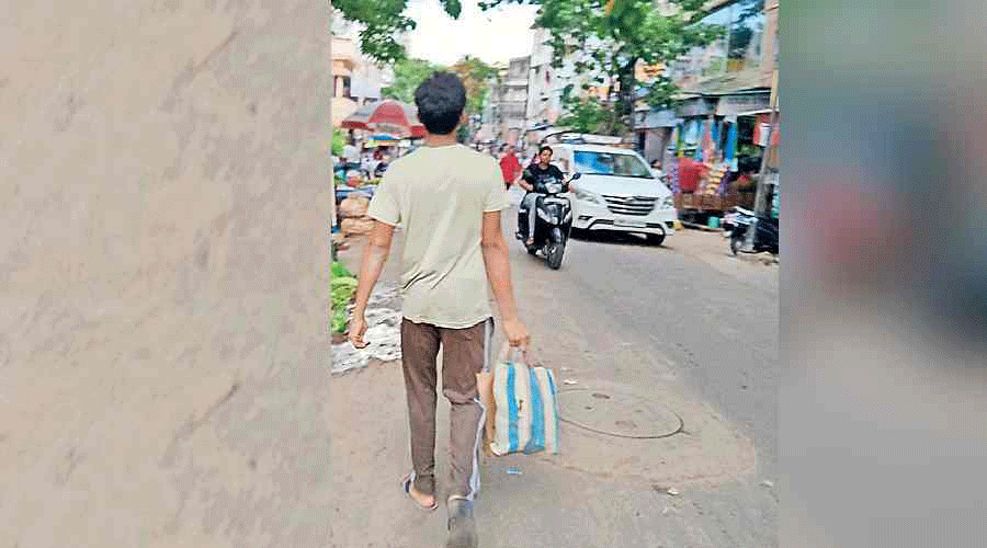 A man returns from the market in Bangur Avenue with two bags brought from home full of goods purchased.