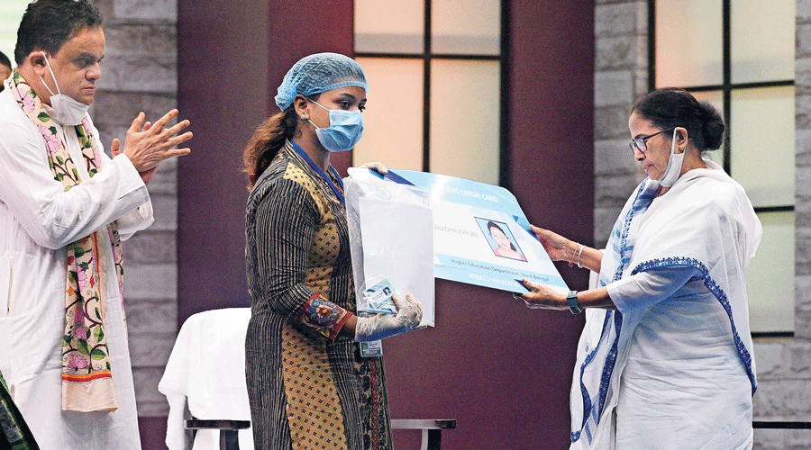 Mamata Banerjee hands over student credit card to a girl at Netaji Indoor Stadium, Calcutta, as state education minister Bratya Basu looks on.