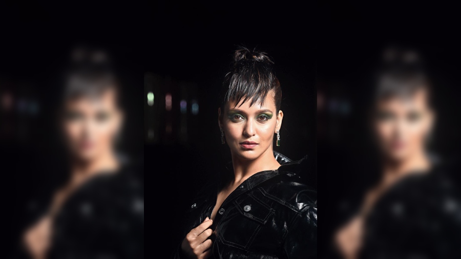 The black leather jacket dress from Zara is accentuated with vibrant make-up. Two shades of green — dark shimmery and lime — create the green smoky look, completed with nude lips, glossy make-up and a fuss-free topknot with fringes on one side of the forehead.