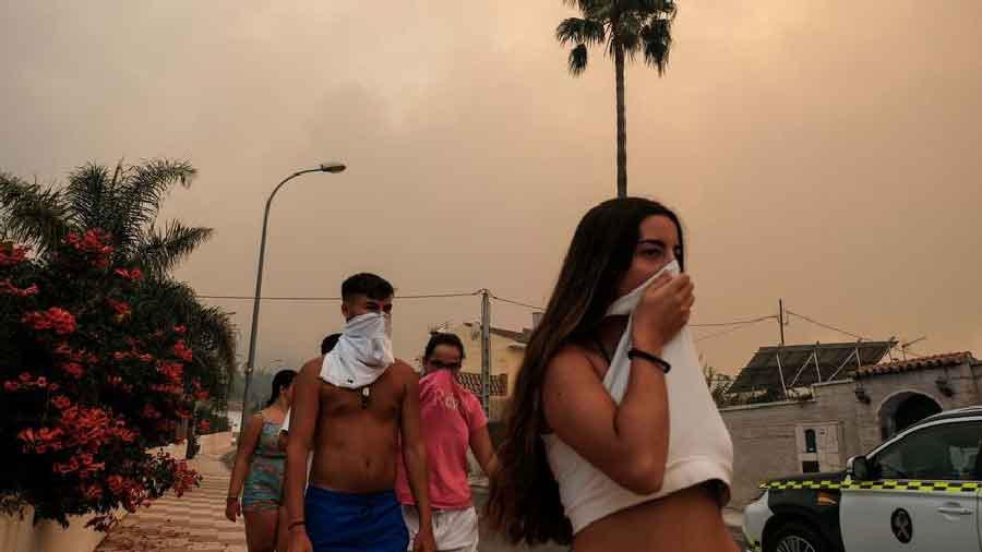 Residents protect themselves from the smoke as a wildfire advances near a residential area in Alhaurin de la Torre in Malaga