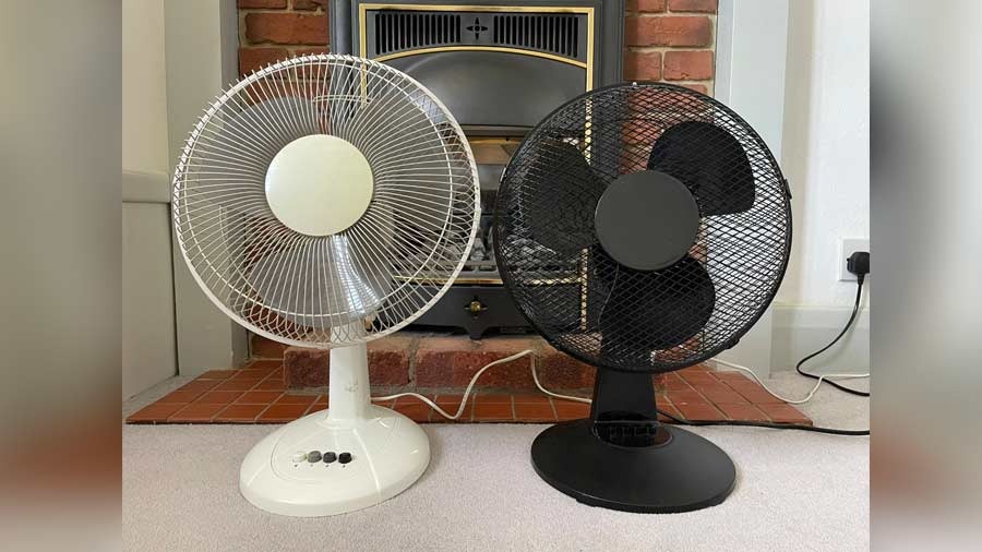 The author’s two desk fans in front of his fireplace 