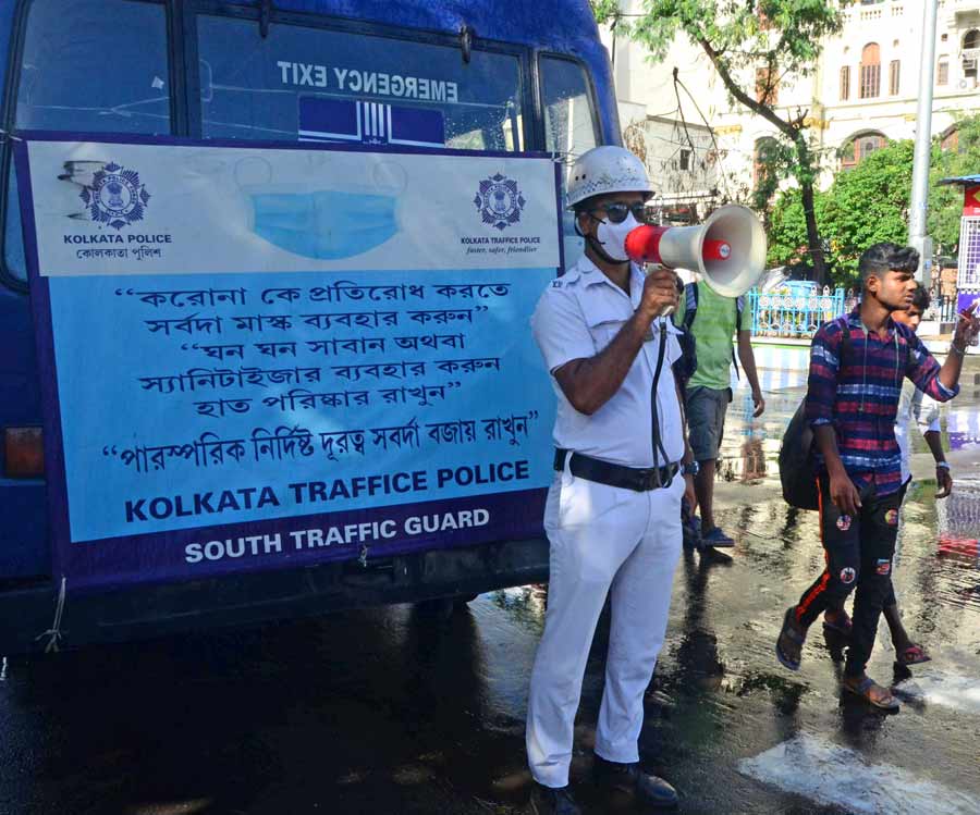 A policeman uses a megaphone near Esplanade to encourage people to follow Covid protocol amid a surge in the number of cases in West Bengal on Sunday. The state reported 1,449 new cases on Monday.