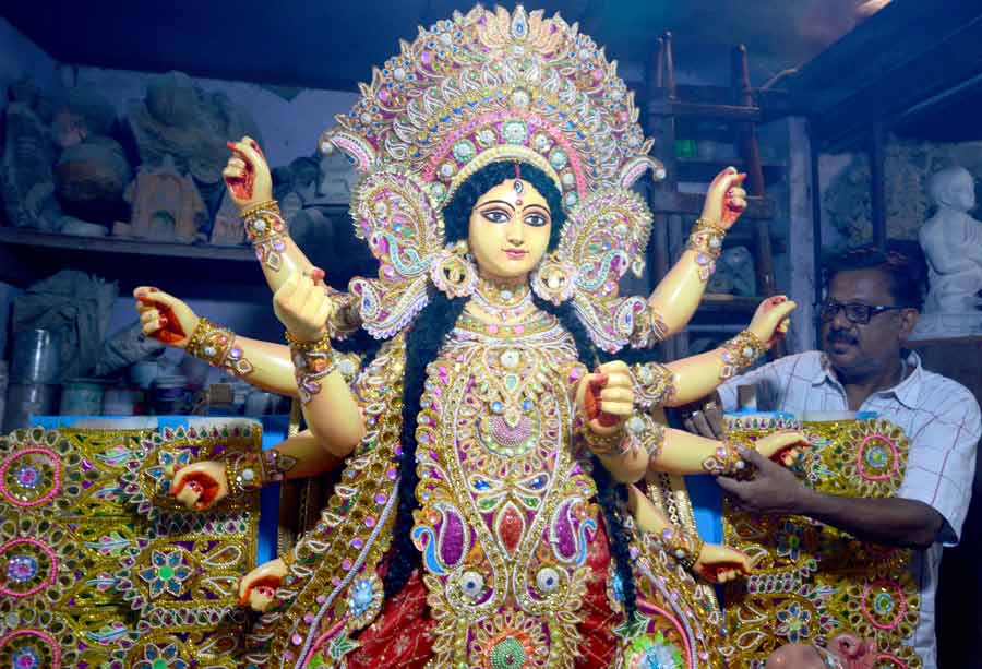 An artist gives finishing touches to an idol of the goddess Durga at Kumartuli on Monday. The idol is bound for Manchester, England.