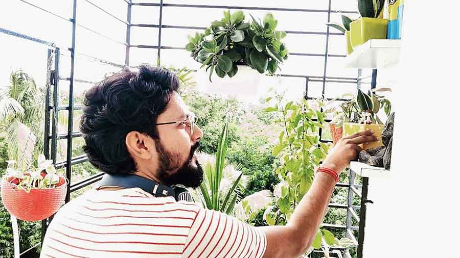 Ashutosh Anurag places a pot on a shelf in his balcony.