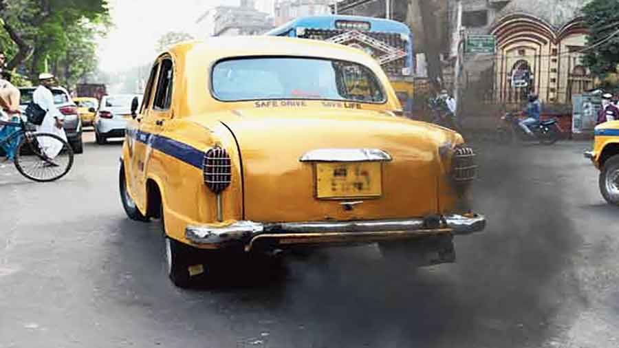 A taxi belching black fumes in the city. 