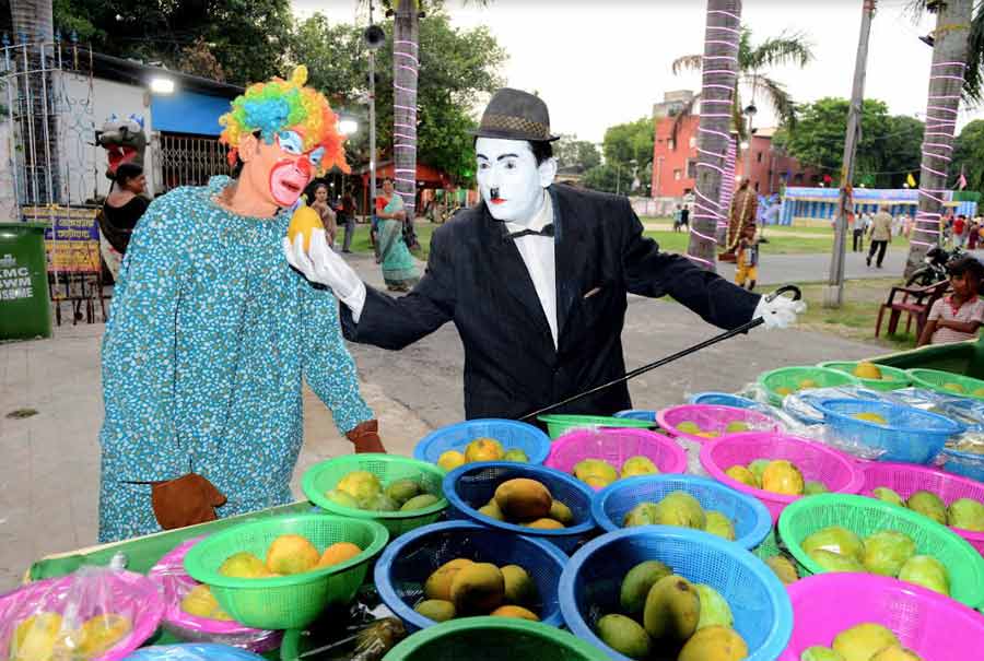 A man dressed as ‘The Tramp’ a la Charlie Chaplin attempts to cheer up a clown with mango varieties at an event in the city on Friday. 