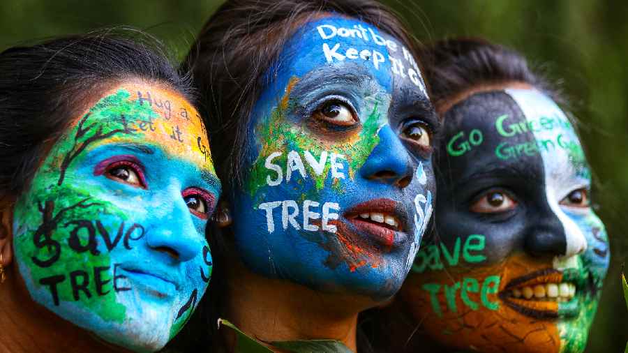 Girls paint their faces with the message of saving the environment, on the eve of the World Environment Day in Nagpur