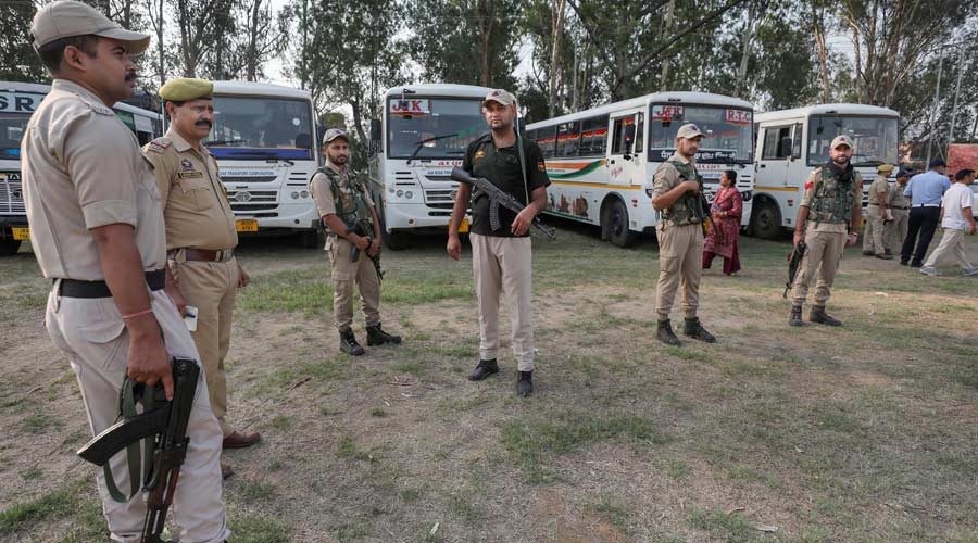Security personnel stand guard as migrant Kashmiri Pandits leave for the annual Kheer Bhawani Mela from Jammu on Tuesday.