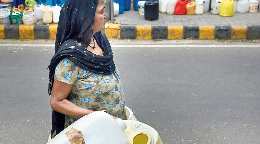 A woman carries vessels to fill with drinking water from a tanker, amid a water crisis and a heat wave, at the Vivekananda Camp in New Delhi on May 20.