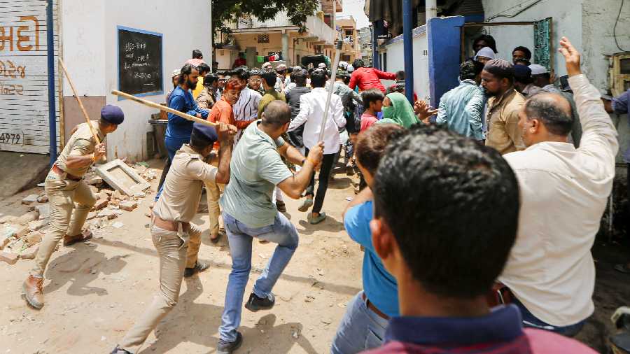 Police personnel chase away people during their protest demanding arrest of former BJP spokesperson Nupur Sharma over her remarks against Prophet Muhammad, in Ahmedabad