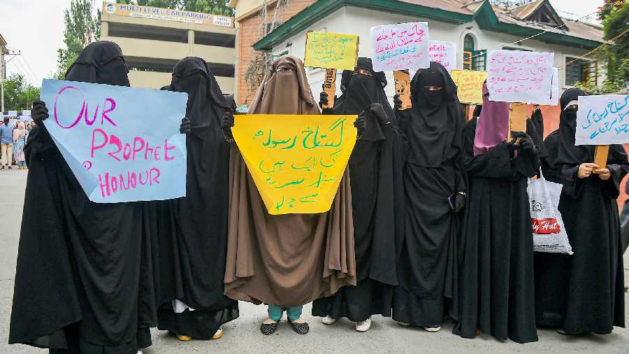 Veiled Muslim women hold placards during a protest against controversial remarks about Prophet Mohammad, in Srinagar