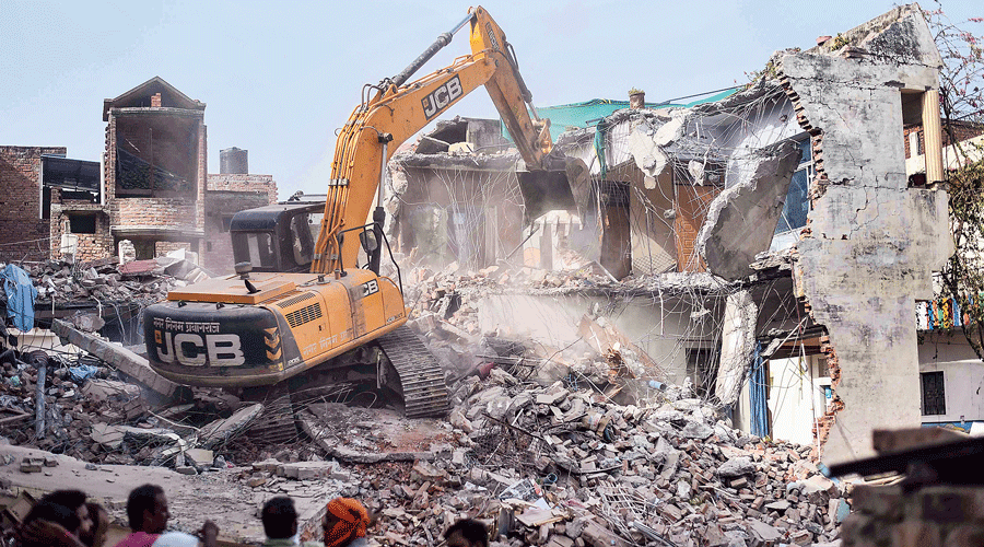 A bulldozer demolishing the allegedly illegal part of the house of Javed Mohammad in Allahabad on Sunday.
