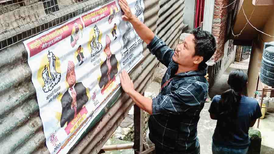 A person puts up a poster in support of a candidate of the Bharatiya Gorkha Prajatantrik Morcha in Kalimpong on Tuesday.