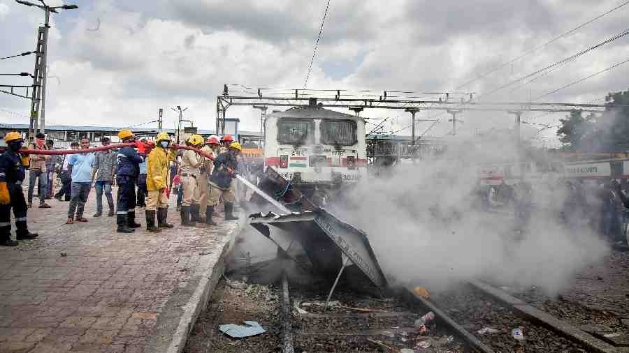 Fire Brigade personnel douse fire on a train set ablaze by a mob in protest against the Central government’s ‘Agnipath’ scheme