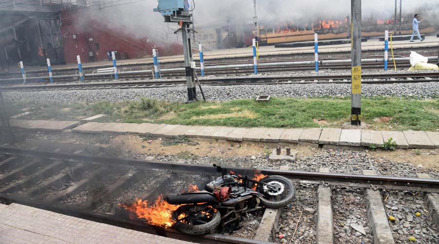 A motorcycle in flames at a railway track after a mob vadalised Farakka Express train and railway properties in protest against the Agnipath scheme, at Danapur Station near Patna on Friday.