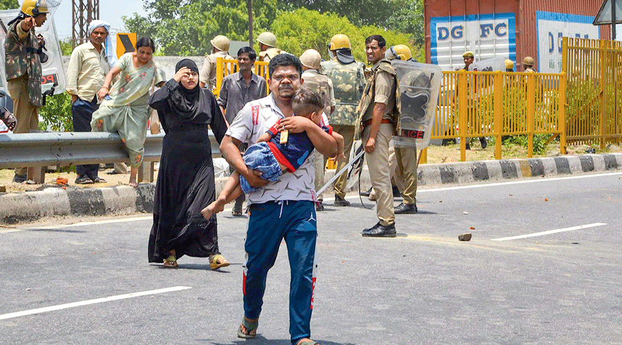 A man with his family heads for a safer place during a clash between the security personnel and protesters on the  Agra-Delhi National Highway in Mathura on Friday.
