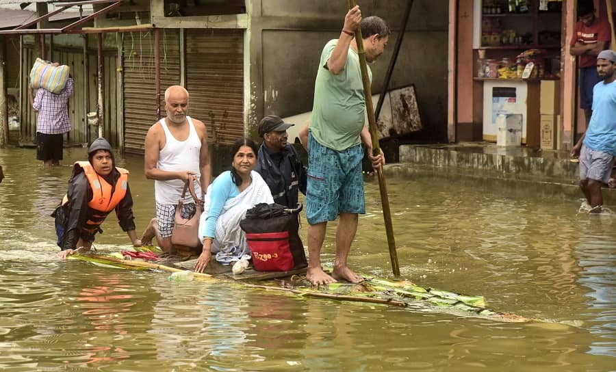 Flood-affected people use a banana raft to shift to safe place, in Bajali district of Assam