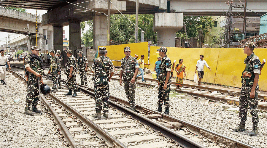 Security personnel stand guard along railway tracks after several trains were cancelled because of the protests against the Agnipath scheme in Patna on Sunday.