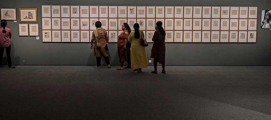A group of visitors admire the artist's pen-and-ink sketches from 1997. 