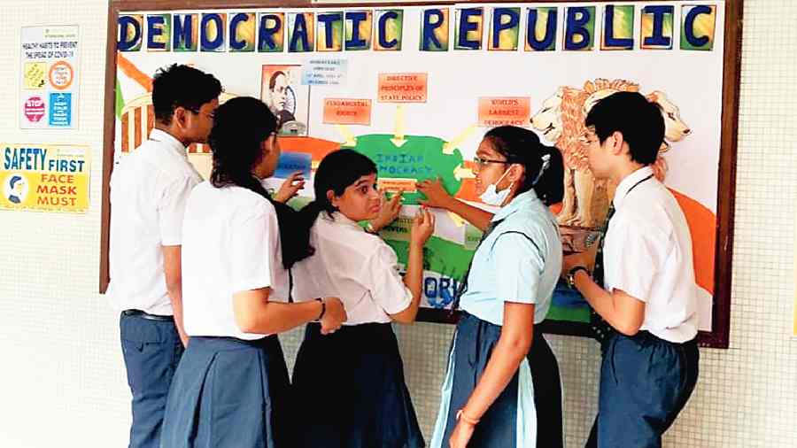 Senior students at South City International School decorate the notice board on Monday morning. The school reopened after summer vacation during the day