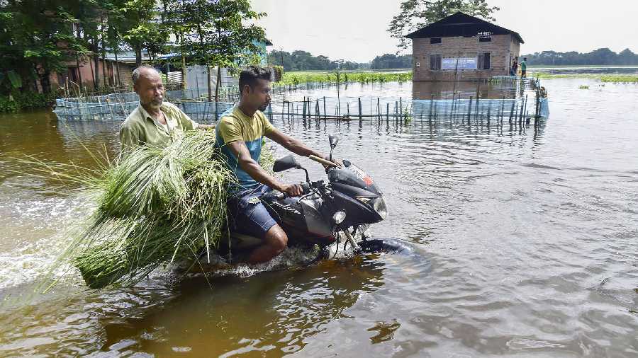  A motorcyclist wades through a flooded road, in Kamrup district of Assam