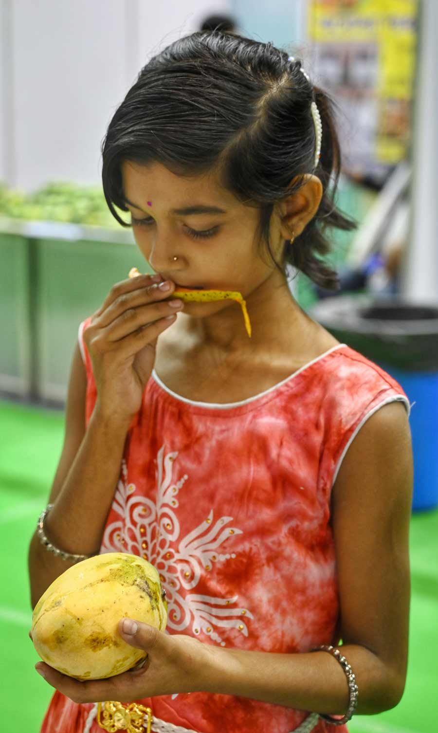 A girl peels a mango and tastes it at the festival.