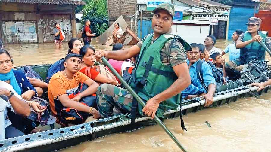 Security personnel ferry on a boat rescued people from a flood-affected area in Silchar on Monday. 