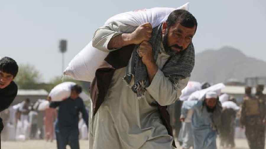 An Afghan man carries a sack of rice, as part of humanitarian aid sent to Afghanistan, at a distribution center in Kabul.