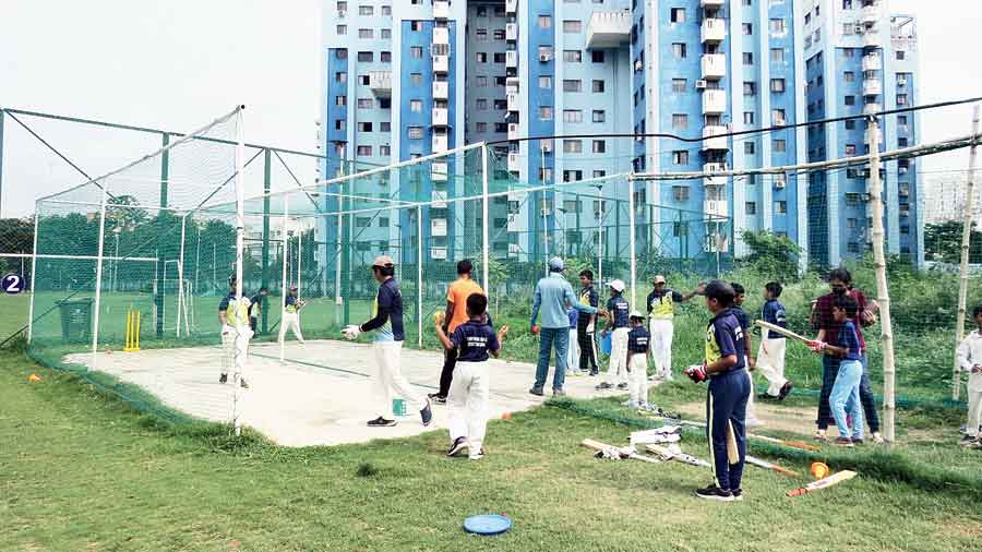 Cricket coaching under way in nets put up outside the fenced-off playground in BA Block 