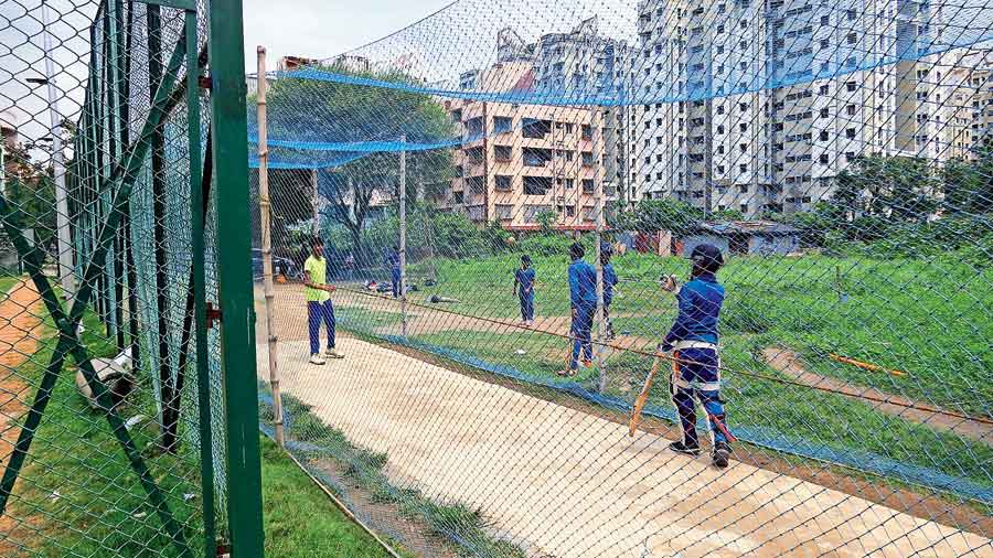 Cricket coaching under way in nets put up outside the fenced-off playground in CB Block 
