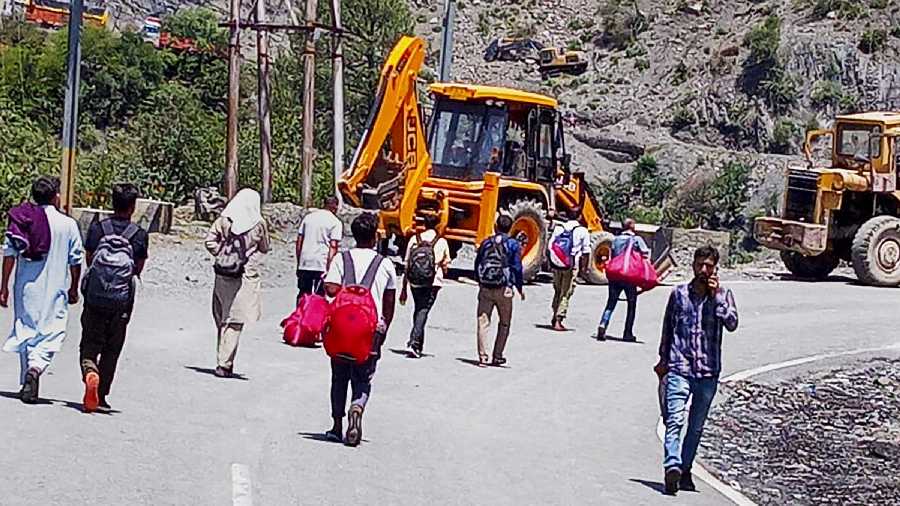 People walk on foot after the National Highway was blocked following landslides due to rains, in Ramban sector