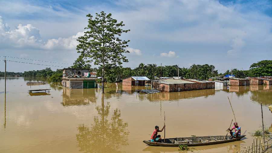 Villagers use a boat to commute through the flooded Chaparmukh village, in Nagaon district