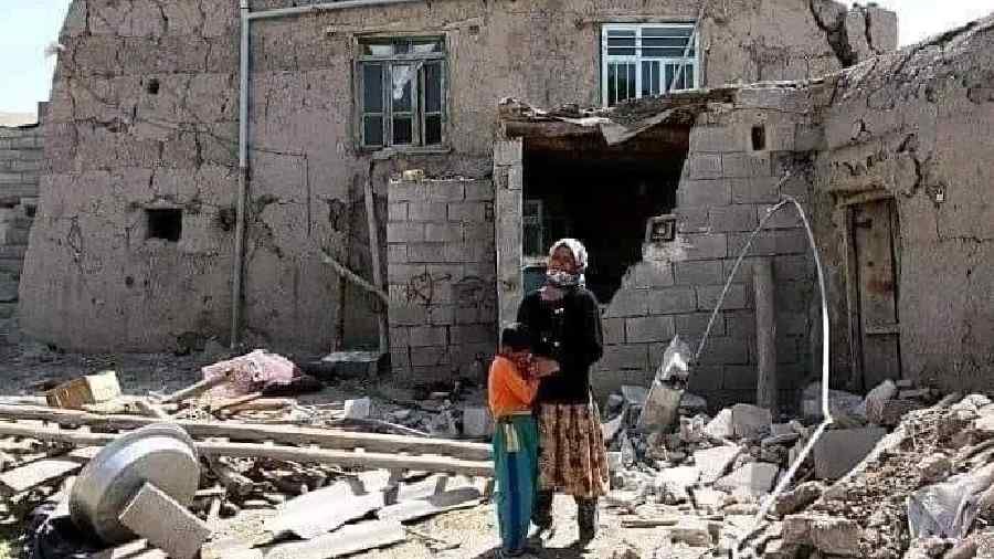 An Afghan family in front of their broken house.