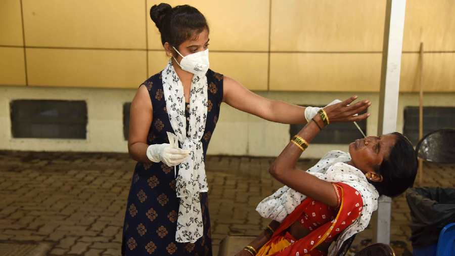 A medic collects swab sample of a woman for COVID-19 test, at Meenatai Thackeray Hospital, in Navi Mumbai