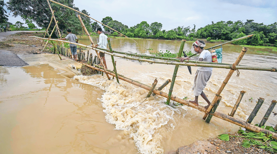 Villagers use a makeshift bamboo bridge in Assam’s Nagaon on Sunday after a portion of a road was washed away.