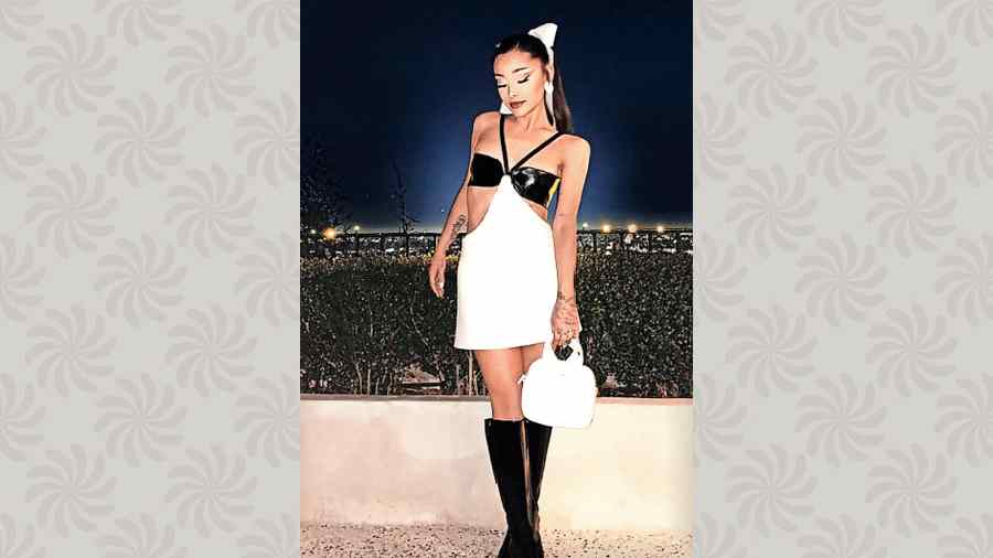 How cute does Ariana Grande look from her March calendar in an Instagram post for her beauty brand r.e.m. beauty? We think super duper cute. The white bow hair tie and black high boots add to the look.