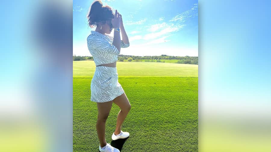 Lush green meets azure sky at a private golf club in Arizona, as the actress-producer-entrepreneur and restaurateur strikes a pose in a zebra print coord. 