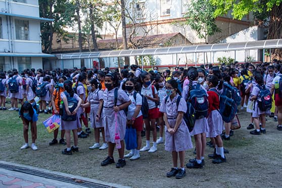 Students queue up on the ground before entering their classrooms.  