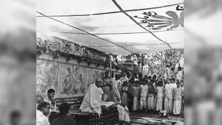 Mahatma Gandhi at Sriniketan, 1941, in front of the Halakarshana mural by Nandalal Bose in Cheap Kuthi