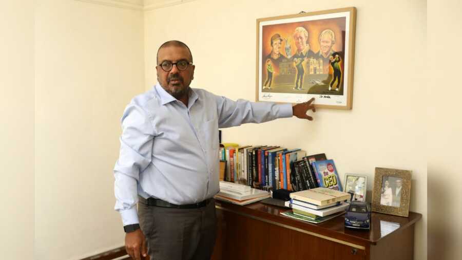 Gaurav Ghosh points at the print hanging on his office wall signed by Gary Player and Arnold Palmer