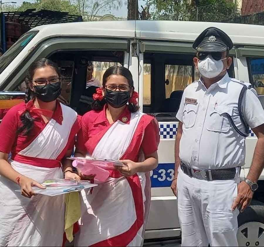 Two Madhyamik examinees with (right) inspector Soumik Sengupta of the Shyambazar traffic guard on Friday. The car ferrying the students to their exam venue had broken down on RG Kar Road. Inspector Sengupta came to their rescue and gave them a lift in a police car, helping the students reach the exam hall in time