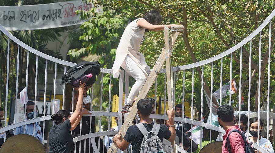 A student scales the Presidency University main gate to play Holi on campus