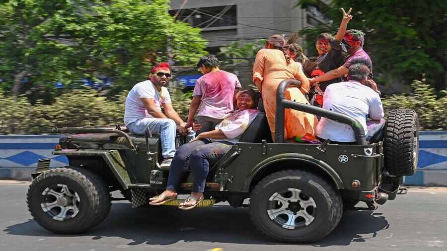 Holi revellers pass a south Kolkata thoroughfare in an open jeep on Friday. 