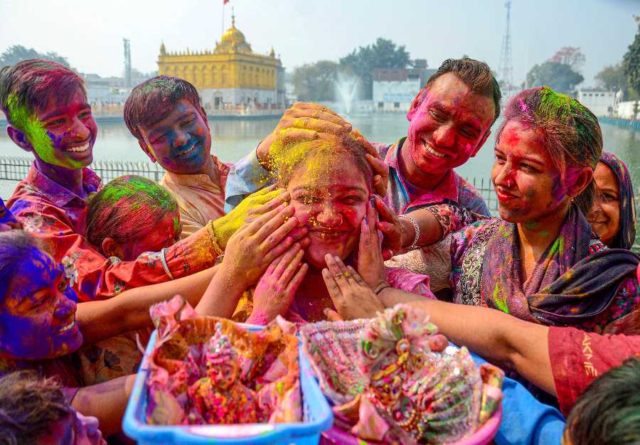 People smear colour on each others faces, in celebration of the festival of Holi at Durgiana Temple, in Amritsar.