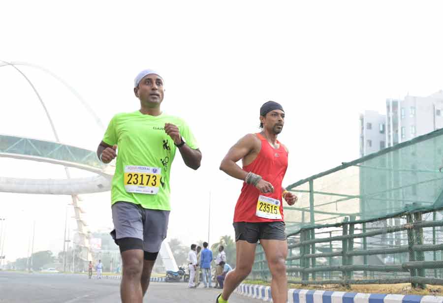 Participants in a marathon race run past the Biswa Bangla Gate on Sunday