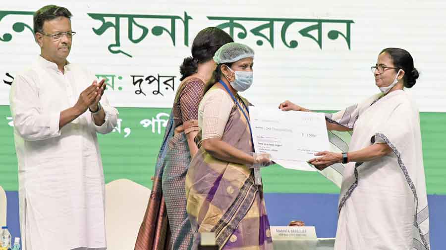 Chief minister Mamata Banerjee with a beneficiary at a programme at Netaji Indoor Stadium on Wednesday where allowances were handed to widows.