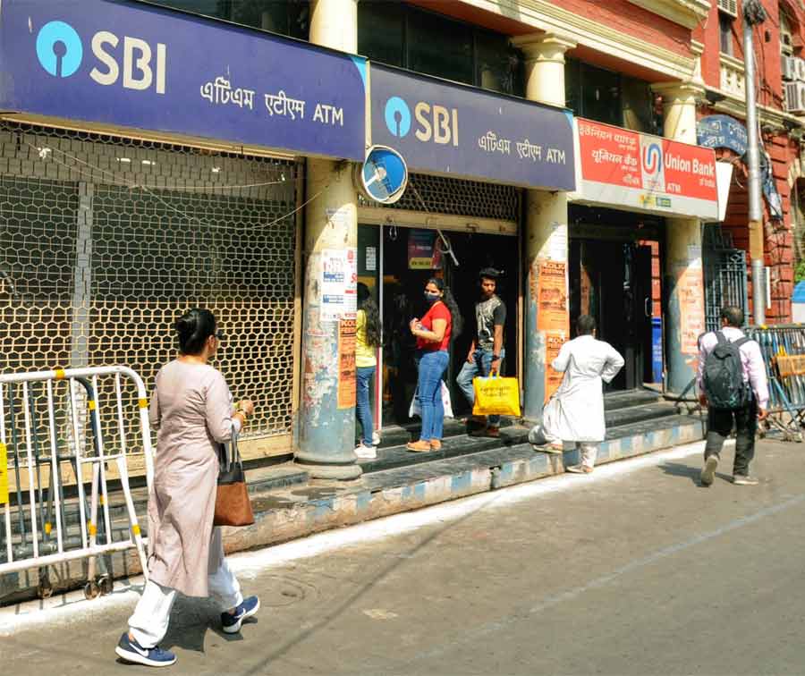 People wait outside an ATM on Monday afternoon. Banking services across the city took a hit on Monday as the two-day nationwide strike began today