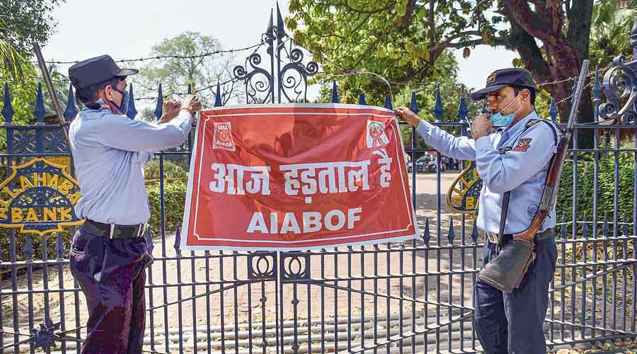 Security personnel stand guard outside a bank in Allahabad on Monday, holding a banner that says: “There is a strike today.”