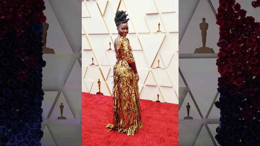 Shining on the red carpet since forever now, Lupita Nyong’o dazzled in a golden Prada gown with pink sequin flowers and shards. The actress carried off the high-shine outfit with her steady confidence.